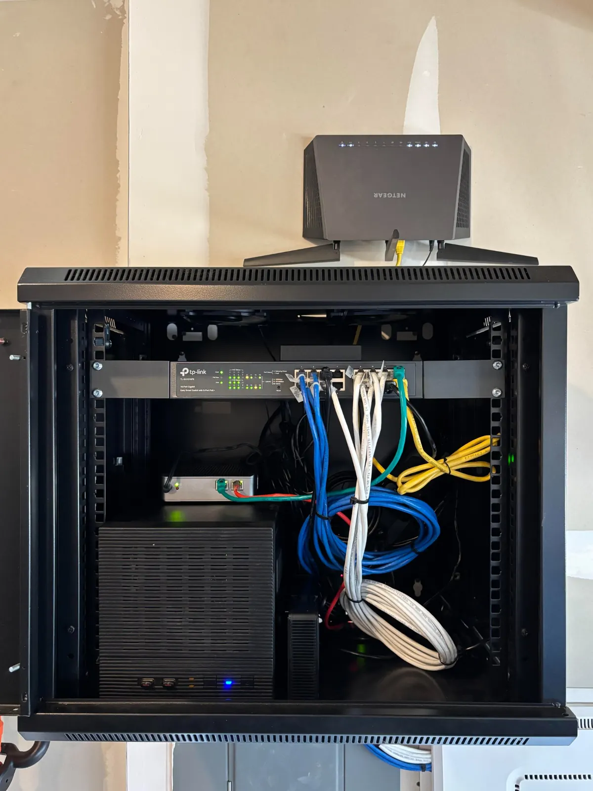 Wall mounted network rack with TP-Link switch and connected network cables